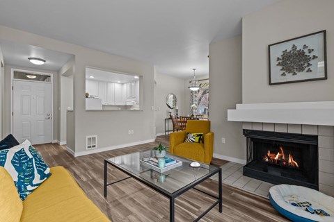 A living room with a yellow couch and a fireplace.